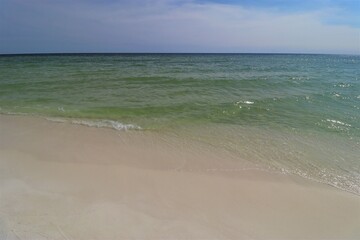 Close-up green wave on the ocean shore, small wave creates foam, shooting from the beach