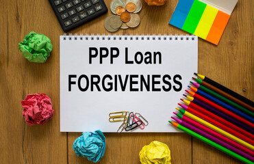 White note with words 'PPP Loan forgiveness' on beautiful wooden table, colored paper, colored...