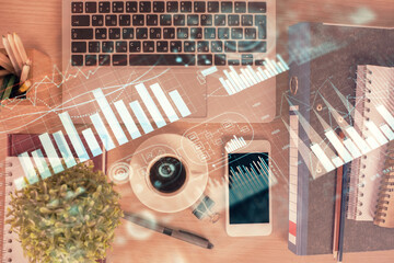 Double exposure of financial graph hologram over desktop with phone. Top view. Mobile trade platform concept.