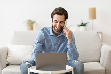 Man Talking On Cellphone Using Laptop Working Remotely From Home