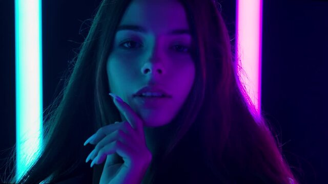 Portrait of a pretty young beautiful woman with hair flying in the wind passionately looking at the camera and touches face with hands. Close up. Slow motion.