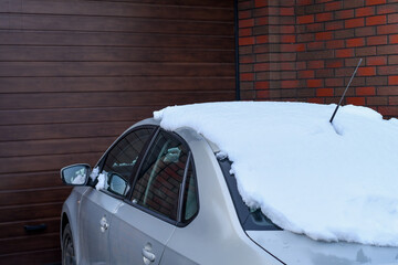 Detail of a car parked near the garage door in winter. Selective focus.