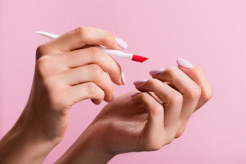 cropped view of woman using cuticle pusher isolated on pink, stock image