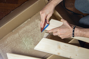 a man sands a wooden board with sandpaper at home, DIY