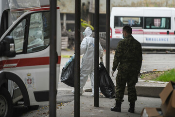 Paramedics in full personal protective clothing disinfecting and cleaning an infectious medical trash of corona virus, covid-19.