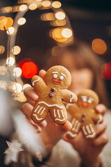 selective focus, noise effect: Merry Christmas and Happy New Year! Christmas cookies, gingerbread man figure holding a smiling woman in her hands