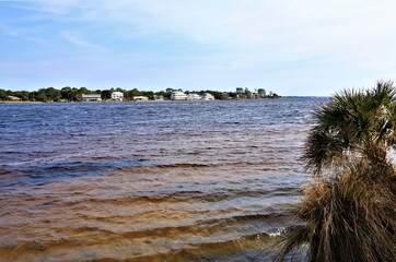 A beautiful view of the mainland from opposite coast of the Gulf of Mexico, from Santa Rose Island, the blue waters of the ocean gleam with the brownish-yellow color of the clay bottom