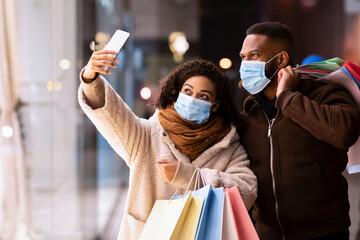 Black couple in masks taking selfie after shopping - obrazy, fototapety, plakaty
