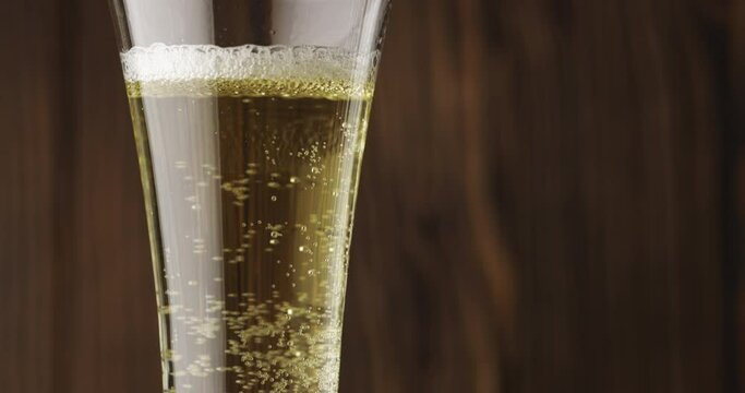 Cold beer is slowly poured into a glass on a dark wooden background, there is a lot of foam and bubbles in the glass. Slow motion. Beer is pouring into a glass isolated on a wooden background. 
