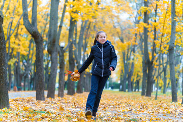 a girl running through the park and enjoys autumn, beautiful nature with yellow leaves