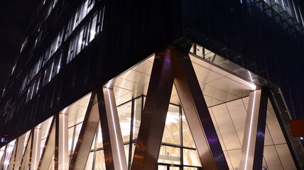 Combination of metal and glass wall material. Steel facade on columns. Abstract modern architecture. High-tech minimalist office building. Contemporary business architecture abstract fragment in night