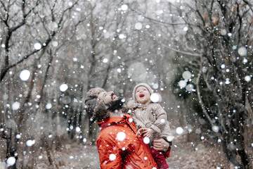 Happy loving family! Father and his baby are playing and hugging outdoors. Little child and daddy on snowy winter walk in nature. Concept of the first long-awaited winter snowfall
