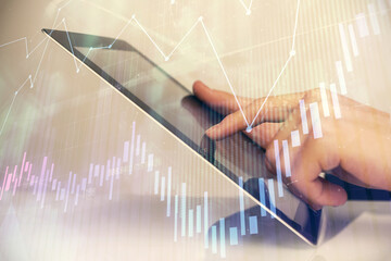 Multi exposure of man's hands holding and using a digital phone and forex graph drawing. Financial...