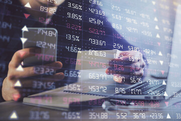 Double exposure of man's hands holding and using a phone and financial graph drawing. Analysis concept.