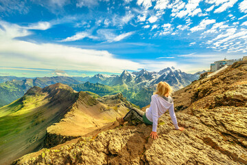 Naklejka premium Tourist woman after hiking, looking amazing panorama 360 degrees surrounding 200 peaks and Eiger, Monch and Jungfrau peaks from Schilthorn viewpoint in Bernese Oberland, Jungfrau Region.