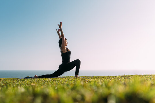 Mujer delgada practica yoga. Mujer haciendo yoga al aire libre estira su cuerpo y sus brazos al cielo.
