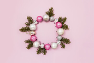 Decorative wreath of pink and silver balls and spruce branches on pastel background. New year or Christmas greeting card. Copy space