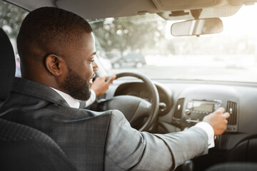 African american businessman turning on music in car before moving