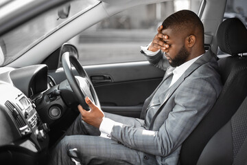 Tired black businessman having troubles at work, sitting in car