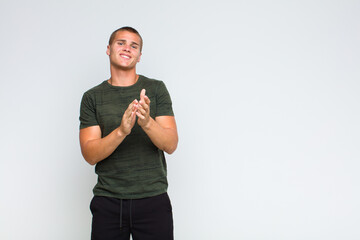blonde  man feeling happy and successful, smiling and clapping hands, saying congratulations with...