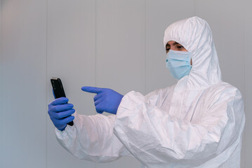 A doctor in PPE consulting mobile application on smartphone during coronavirus
