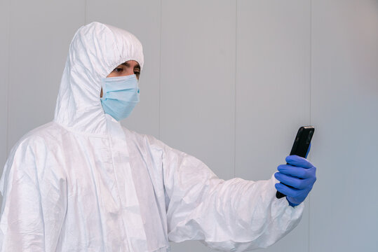 A doctor in PPE consulting mobile application on smartphone during coronavirus - Powered by Adobe