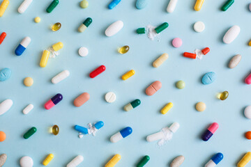 Creative layout of colorful pills and capsules on blue background. Minimal medical concept....