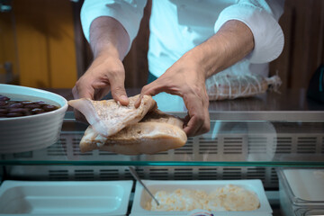 detail of the chef's hands accommodating cured meat, ready for sale