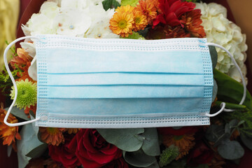 Medical blue face mask with bouquet of flowers.