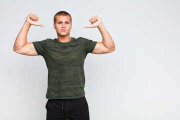 blonde  man feeling proud, arrogant and confident, looking satisfied and successful, pointing to...