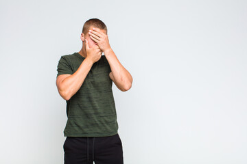 blonde  man covering face with both hands saying no to the camera! refusing pictures or forbidding...