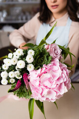 Close up view of fresh bouquet with blurred female florist on background