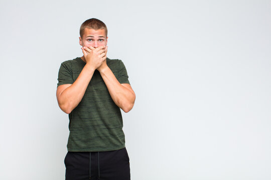 blonde  man covering mouth with hands with a shocked, surprised expression, keeping a secret or saying oops