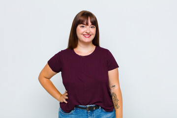 overweight woman smiling happily with a hand on hip and confident, positive, proud and friendly...