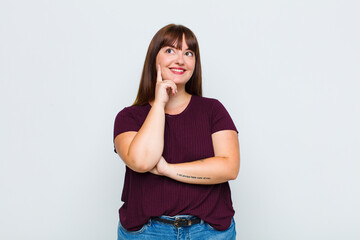 overweight woman smiling happily and daydreaming or doubting, looking to the side