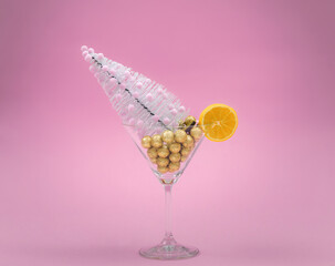 Christmas tree with pink decoration in cocktail glass on pink background. Christmas composition. New year minimalistic composition. Holiday concept.