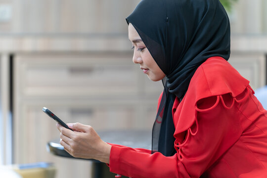 happy face muslim woman in red dress with smartphone.