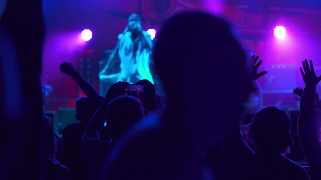 Hip-hop star performing on stage in front of fans. Live concert performance in a club filled with people raising their hands in the air. The concept of partying and fun. Music night gig.