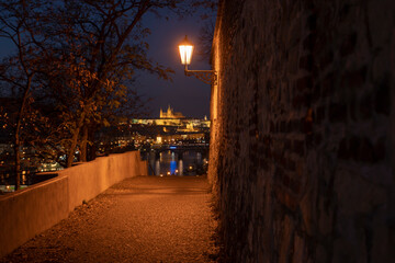 light from street lights and a paved sidewalk for pedestrians at night in the center of Prague in the Czech Republic
