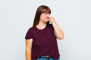 overweight woman feeling disgusted, holding nose to avoid smelling a foul and unpleasant stench