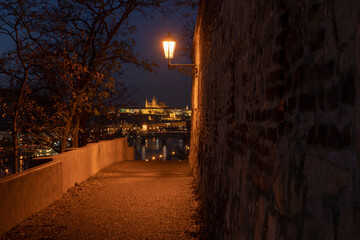 light from street lights and a paved sidewalk for pedestrians at night in the center of Prague in the Czech Republic