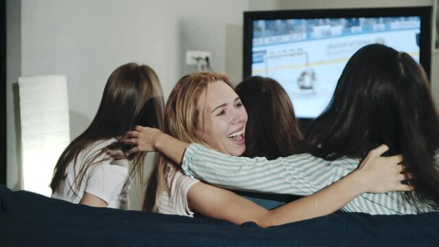 Excited millenials cheering for team sitting in living room. Backshot group of teens watching hockey match on tv celebrating goal. Concept of leisure, lifestyle, spending time together, victory.
