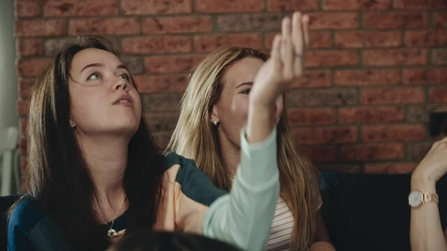 Two pretty girls throwing popcorn and trying to catch it with mouth. Teenagers laughing and compete with each other having a good time spend it together. Concept of youth, fun, fooling around.