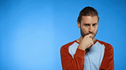 thoughtful young man looking away on blue background