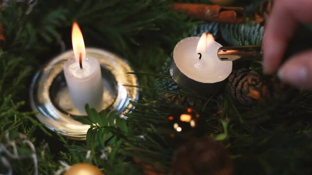 The woman lights a candle on an Advent wreath, the background slightly blurred