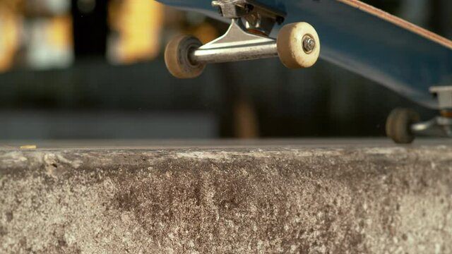 SLOW MOTION TIME WARP, CLOSE UP, DOF: Skater skilfully does a manual along the edge of a concrete ledge. Detailed shot of a balance trick done by unrecognizable skateboarder riding around the city.