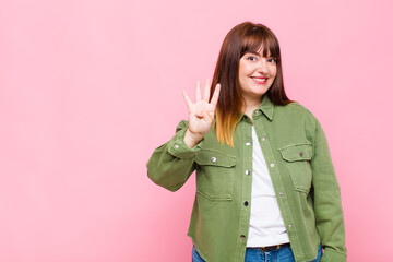 overweight woman smiling and looking friendly, showing number four or fourth with hand forward,...