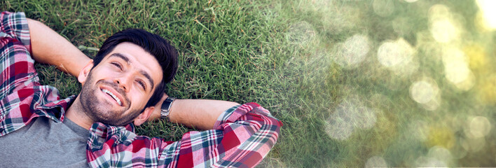 The caucasian man was happily lying on the grass with a bokeh copy space.