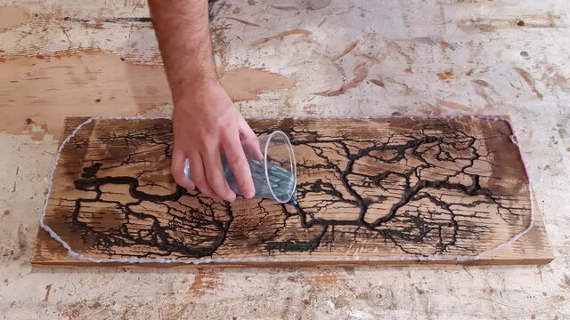 Pouring Epoxy Resin on big wooden board with holes. Beautiful art made with wood and epoxy resin. Burning wood with electricity and water to make interesting holes. Epoxy art filmed in 4k