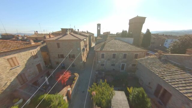 Aerial tilt up over the roofs of the medieval village of Bettolle, Italy. Amazing ancient typical Tuscan town